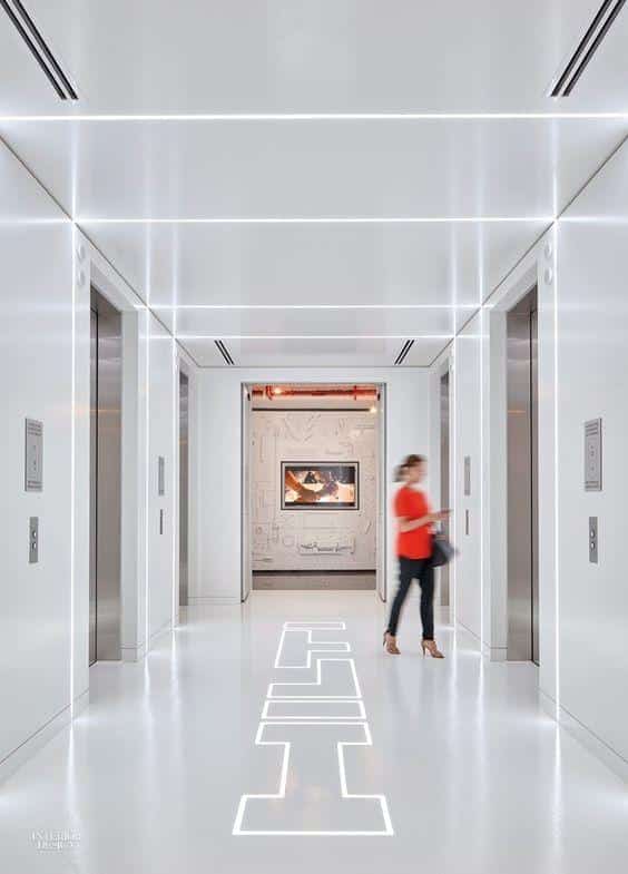 Bright white lift lobby with LED strip lighting across the ceiling and walls and lit letters set into the floor